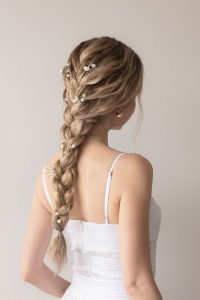 Romantic braided ponytail with soft volume and scattered baby’s breath flowers, ideal for summer events or bridal looks.